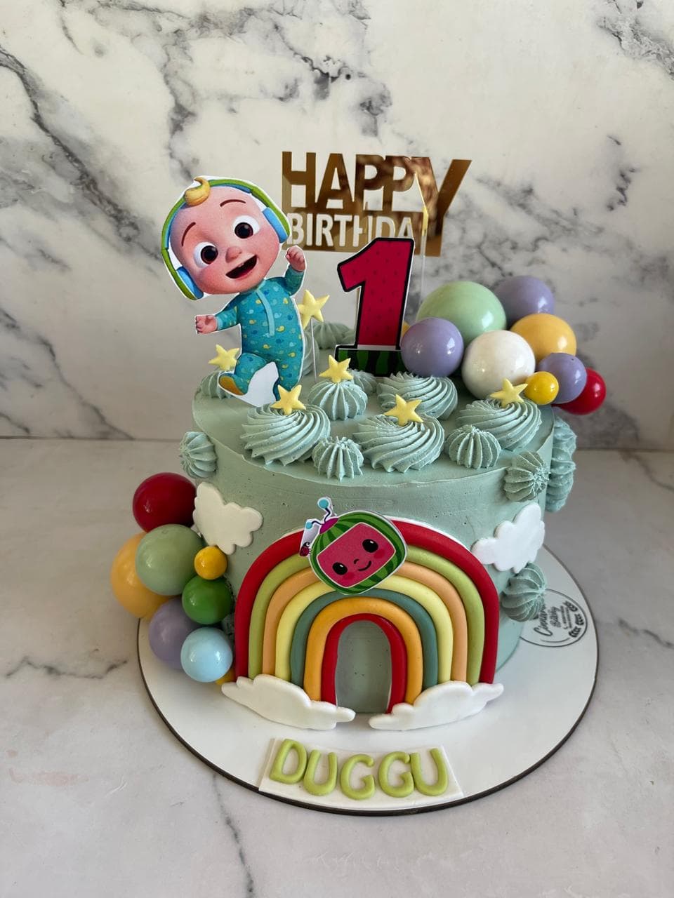 First birthday cake with a rainbow, balloons, and fondant character topper